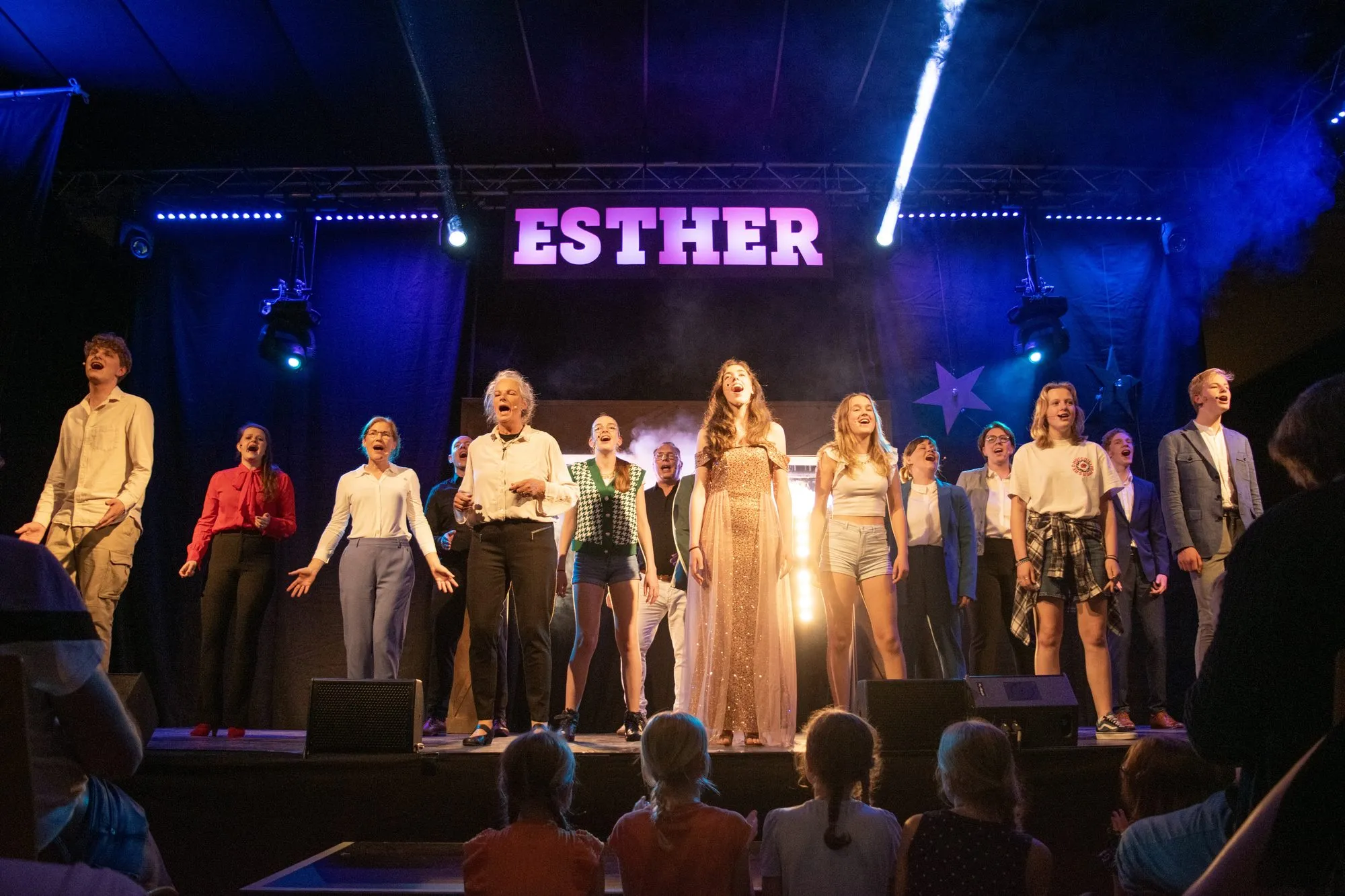 Het ensemble van Esther in fel tegenlicht onder de verlichte titel
