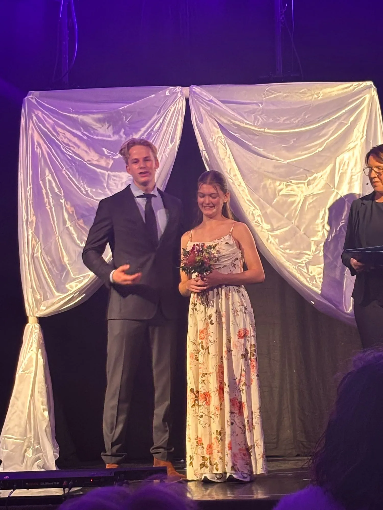 Een bruidspaar op het podium, voor witte draperieën
