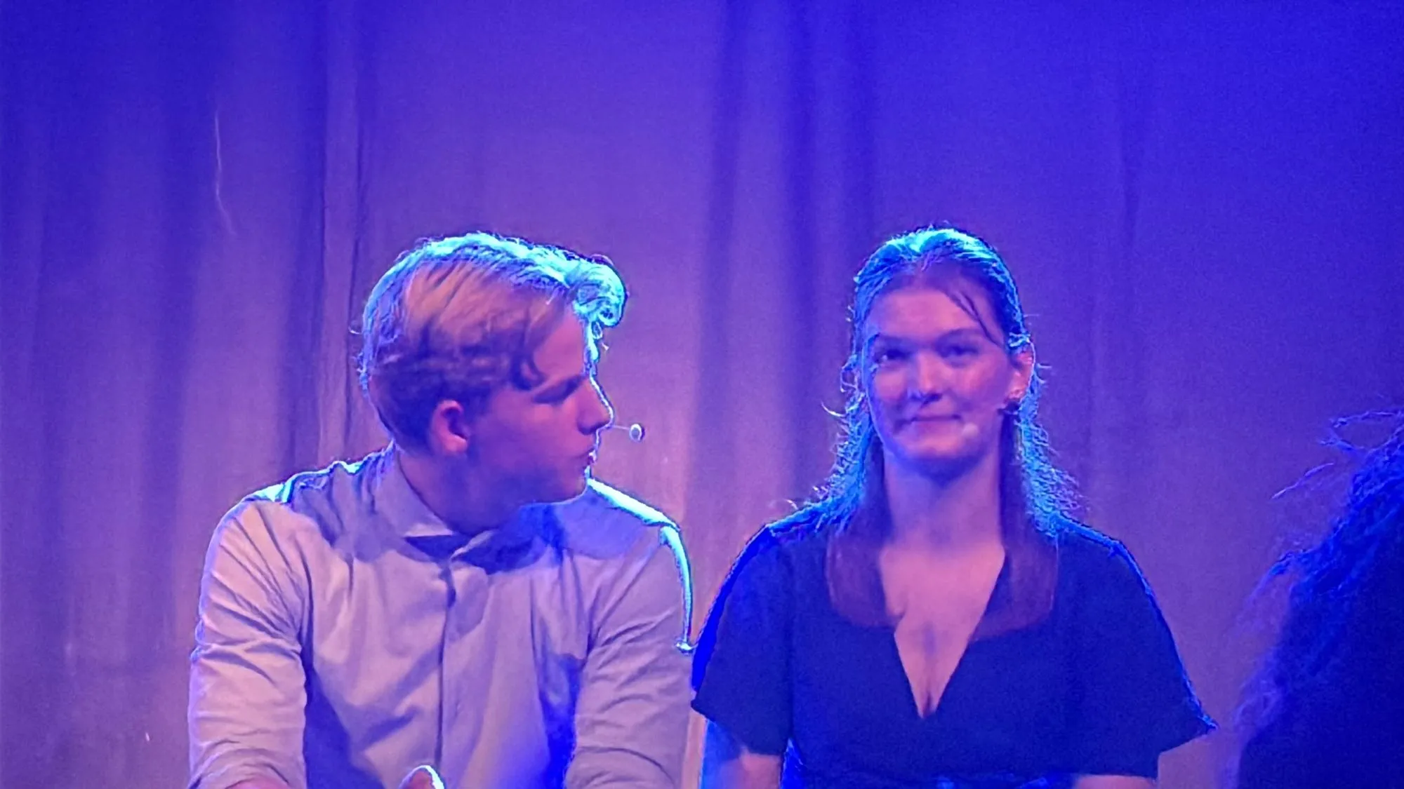 Een jonge man en vrouw zingen samen in blauw licht